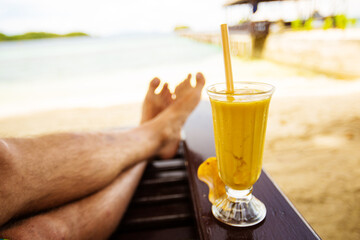 Man drinks mango juice on the beach
