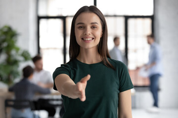 Head shot portrait pretty friendly employer stretch out her hand for hand shake greets applicant, representative of company young confident executive manager welcoming client express respect concept