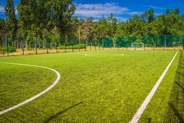 Soccer field with artificial green grass near the school. Amateur football field. Sunny summer day