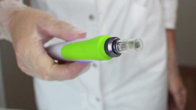 Device for fractional mesotherapy. The cosmetologist holds in his hand an apparatus for fractional mesotherapy. Hardware cosmetology. Microinjection under the skin.Procedures for the beauty.