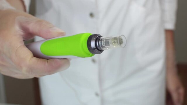 Device for fractional mesotherapy. The cosmetologist holds in his hand an apparatus for fractional mesotherapy. Hardware cosmetology. Microinjection under the skin.Procedures for the beauty.