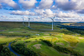 Aerial drone shot of several clean energy wind turbines in a rural area of South Wales, UK