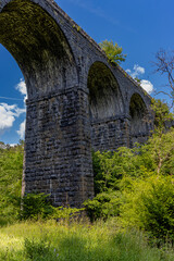 Fototapeta na wymiar Arches underneath an old Victorian viaduct in a beautiful green rural setting (Pontsarn Viaduct, South Wales, UK)