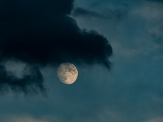Ciemna chmura na tle wschodzącego księżyca.