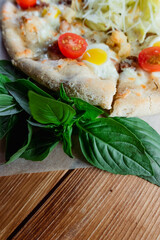 Appetizing pizza on a wooden table surrounded by herbs and spices. The concept of delicious food, restaurants and cafes