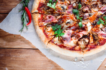 Appetizing pizza on a wooden table surrounded by herbs and spices. The concept of delicious food, restaurants and cafes