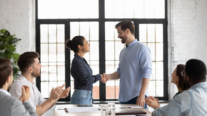 Indian and caucasian business people shake hands start negotiations with partners at boardroom....