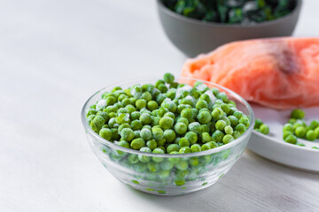 Frozen vegetables and fish: green peas, spinach, salmon. Concept of healthy eating, easy cooking. White background copy space for text. Close up macro