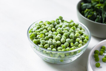 Frozen vegetables: green peas, spinach. Concept of healthy eating, easy cooking. White background copy space for text. Close up macro.