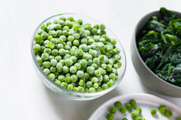 Frozen vegetables: green peas, spinach. Concept of healthy eating, easy cooking. White background copy space for text. Close up macro.