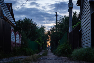 Sunset on the street among small houses in russia suburbia.