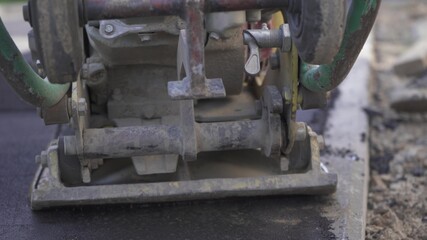 Vibratory asphalt paving machine on the sidewalk filmed close-up.Road works,pavement repair,hard work.Video clip