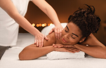 Obraz na płótnie Canvas Young black woman getting massage at spa