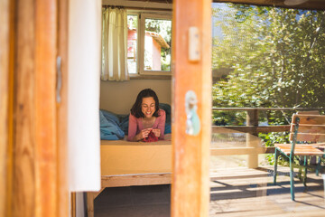 Woman knits while lying on the bed.