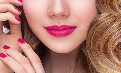 Close up shot of sexy woman lips with pink lipstick and pink manicure Make up concept. Smiling model face in front