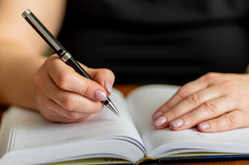 Hand with pen over notebook close-up.