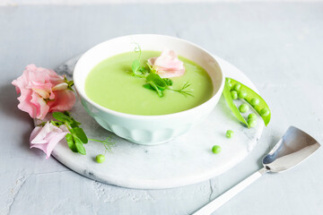 Homemade fresh green pea cream soup with pea sprouts and flowers