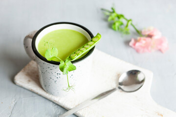 Homemade fresh green pea cream soup with pea sprouts and flowers