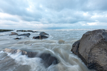 Fototapeta na wymiar Rocks and boulders in the sea at Hoek van Holland The Netherlands. Picture with slow shutterspeed.