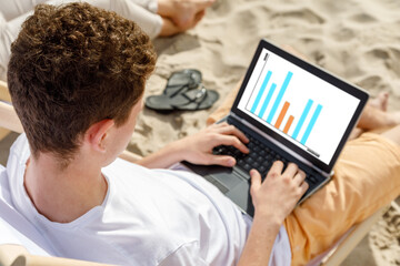 Young man using laptop on beach 
