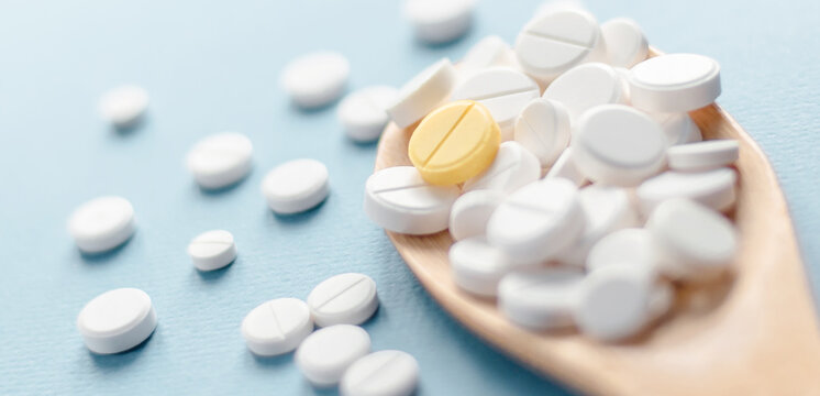 White tablets and one yellow tablet on the blue background.