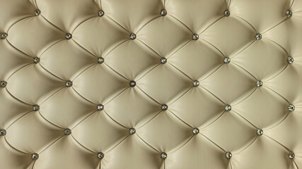 Stylish beige soft leather upholstery of sofa. The material is decorated with buttons in the form of crystals. Upholstery leather pattern background.