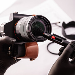 A girl photographer in gloves cleans the lens with special tools for cleaning professional optics....