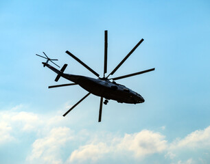 Silhouette of heavy transport helicopter flying against the blue sky