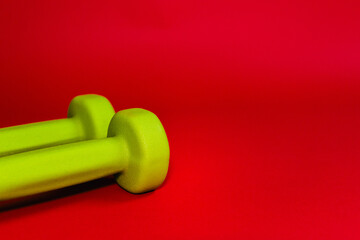 Green dumbbells isolated on a red background. Flatlay concept of fitness, gym and healthy lifestyle. The view from the top and space for copy