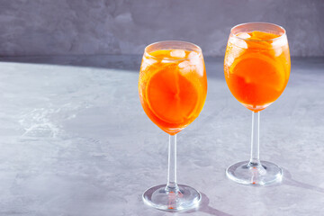Aperol spritz cocktail on gray background. Two glasses of aperol spritz with orange slised. Summer cocktail in glass. Copy space