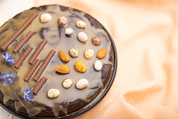 Homemade chocolate brownie cake with caramel cream and almonds with cup of coffee on a white concrete  background. Side view, selective focus.