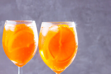 Aperol spritz cocktail on gray background. Two glasses of aperol spritz with orange slised. Summer...