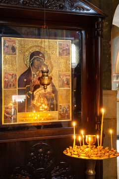 Wax candles burn in front of  icon of the Mother of God