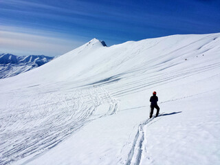 Fototapeta na wymiar Skier on the top of mountain going through fresh snow 