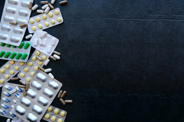 Medicine green and yellow pills or capsules on black background with copy space.
