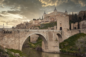 Fototapeta na wymiar Toledo in Spain with Tagus River and Roman bridge Puente de Alcantara. Famous UNESCO World Heritage Site.