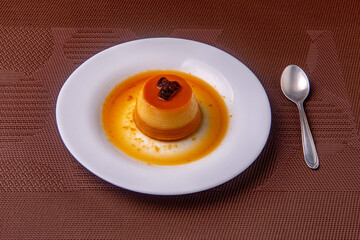 Homemade milk pudding with caramel cream. Traditional Brazilian dessert on a plate on wooden...