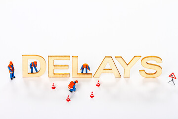 Wooden delays sign with miniature figure workmen and traffic cones