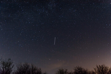 Fototapeta na wymiar Background of the night sky with many stars. Satellite trajectory