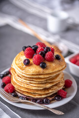 Homemade pancakes with raspberries and blueberries on grey napkin.