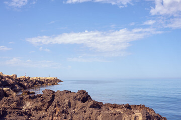 Rocky sea coast of Crete, Greece under a blue sky with white clouds. Copy space.