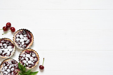 Tartlets with berries on a white wooden background. View from above.