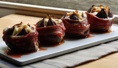 Fototapeta na wymiar Baked prosciutto wrapped Turkish figs stuffed with goat cheese and pine nuts.