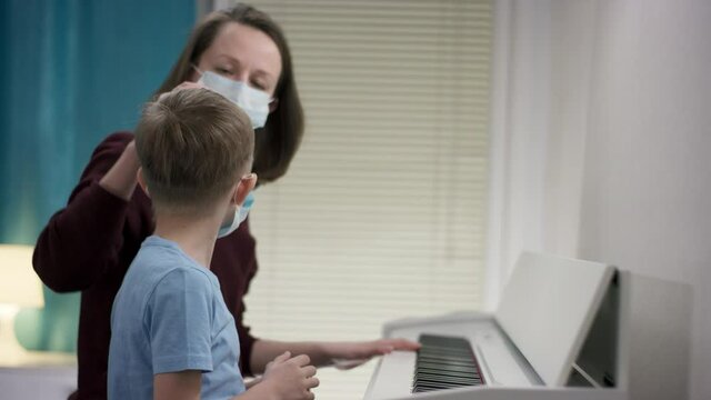 Closeup filming of a mom bracing up her boy to learn playing tunes on the piano by patting his head during Covid19 outbreak