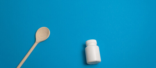 Concept protective equipment against pandemic, coronavirus, top view. Wooden spoon, pills and capsule bottle, thermometer on blue background, isolated. Free, blank space for text. Banner for web site