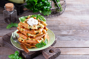 Homemade zucchini cheese waffles with sour cream with basil on a plate. Copy space