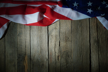 American flag freely lying on the textured wooden background. News template about the America.