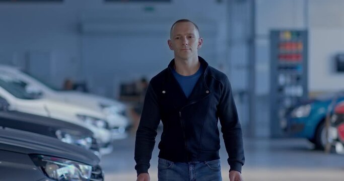 Young handsome guy goes to a car dealership, chooses a new car. Buyer looks a car from a dealer in a salon, an interested look. Car business.