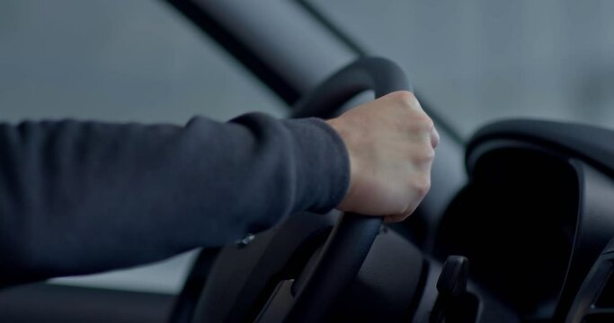 Men's hands hold the car steering wheel tightly. Hands touch the wheel of a new car. Close-up.