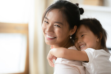 Adorable sweet little preschool kid daughter cuddling from back smiling beautiful vietnamese...